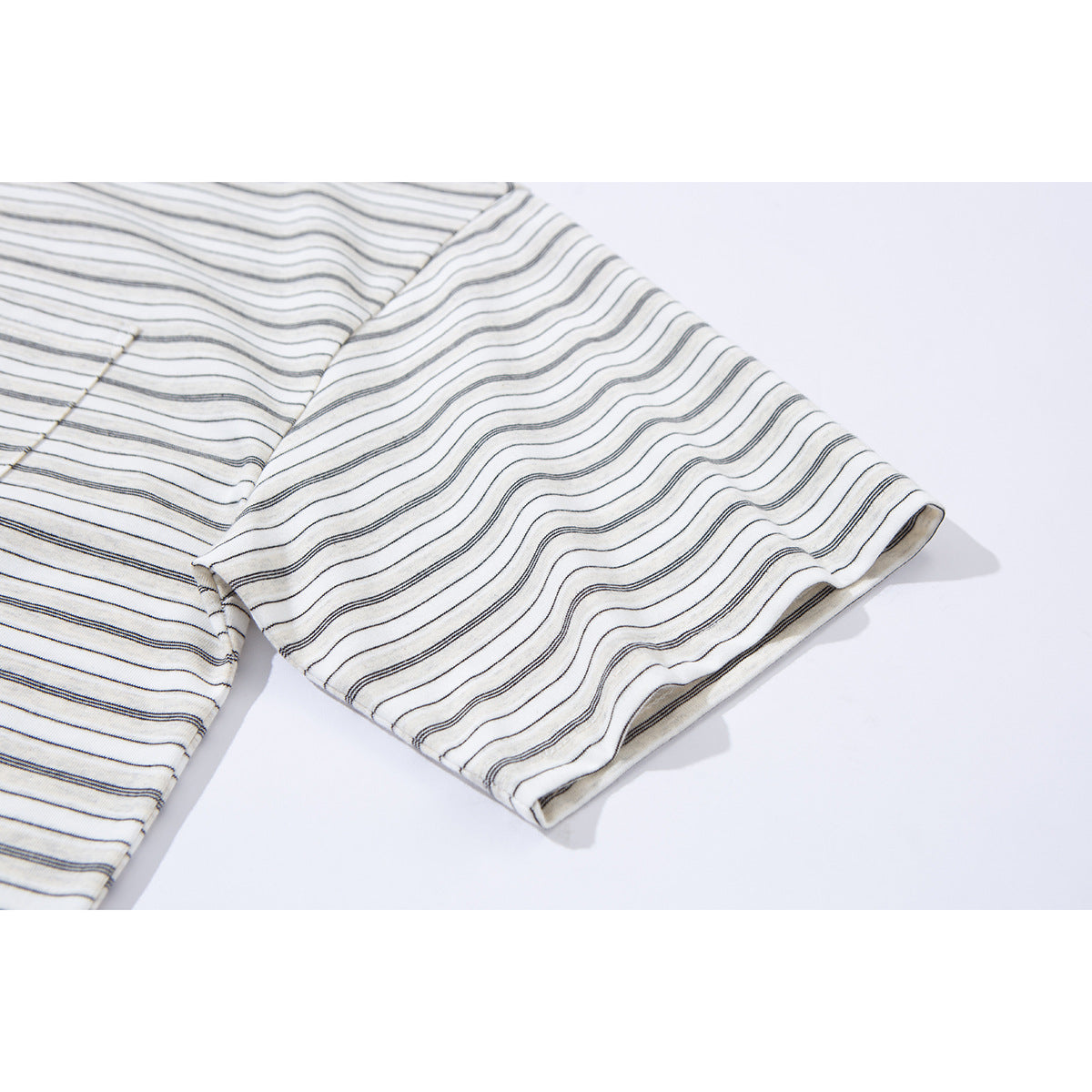 Close-up of a short sleeve on an ivory T-shirt with fine dark stripes.