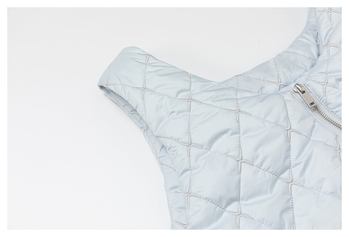 Close-up of pale blue diamond-quilted fabric and silver zipper hardware on the garment.