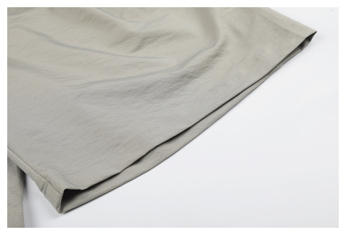 Close-up of the stitched hem on light gray-beige trousers.
