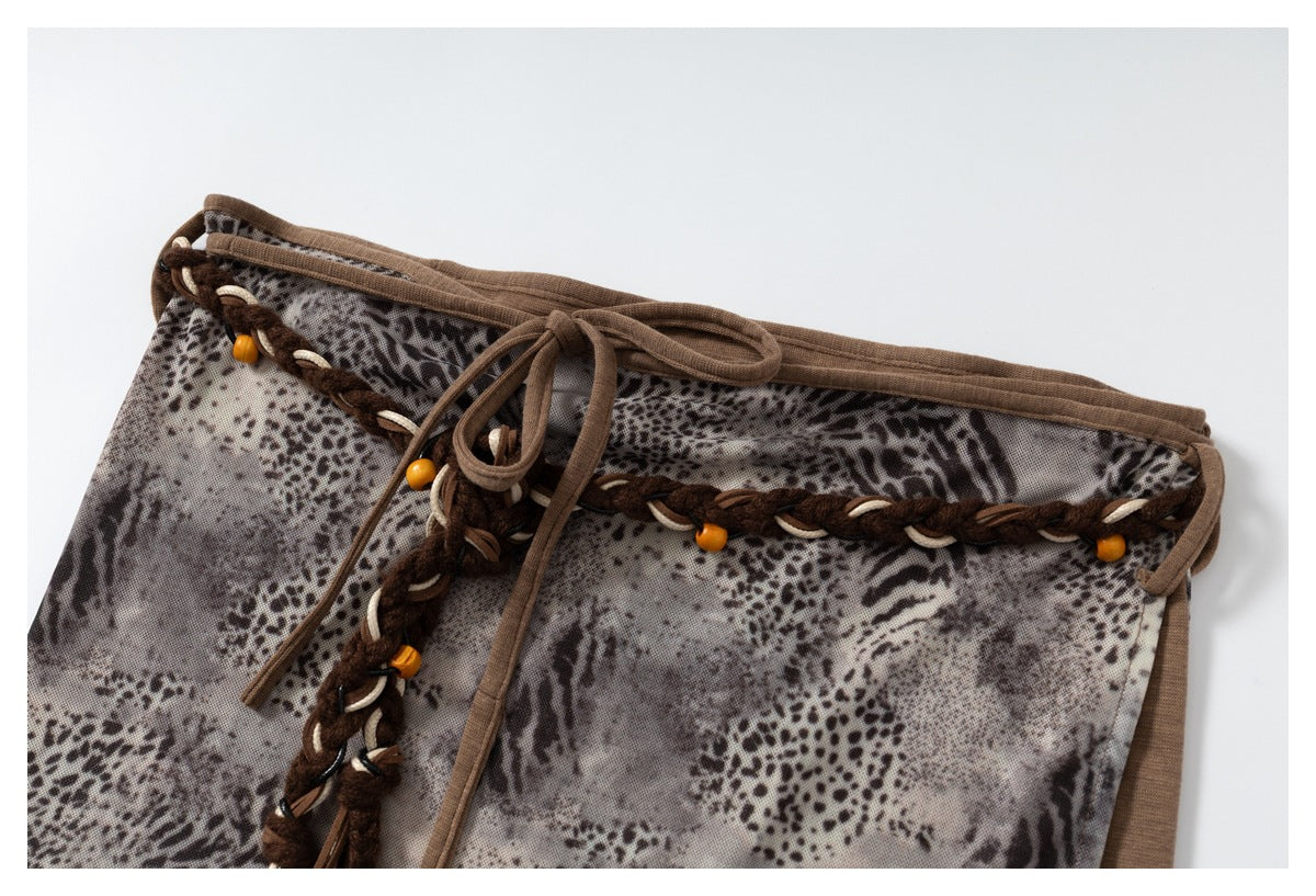 Close-up of the skirt's animal-print fabric, brown drawstring, braided trim, and orange bead accents.