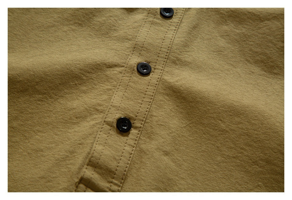 Close-up of a tan garment's stitched placket with three black buttons.