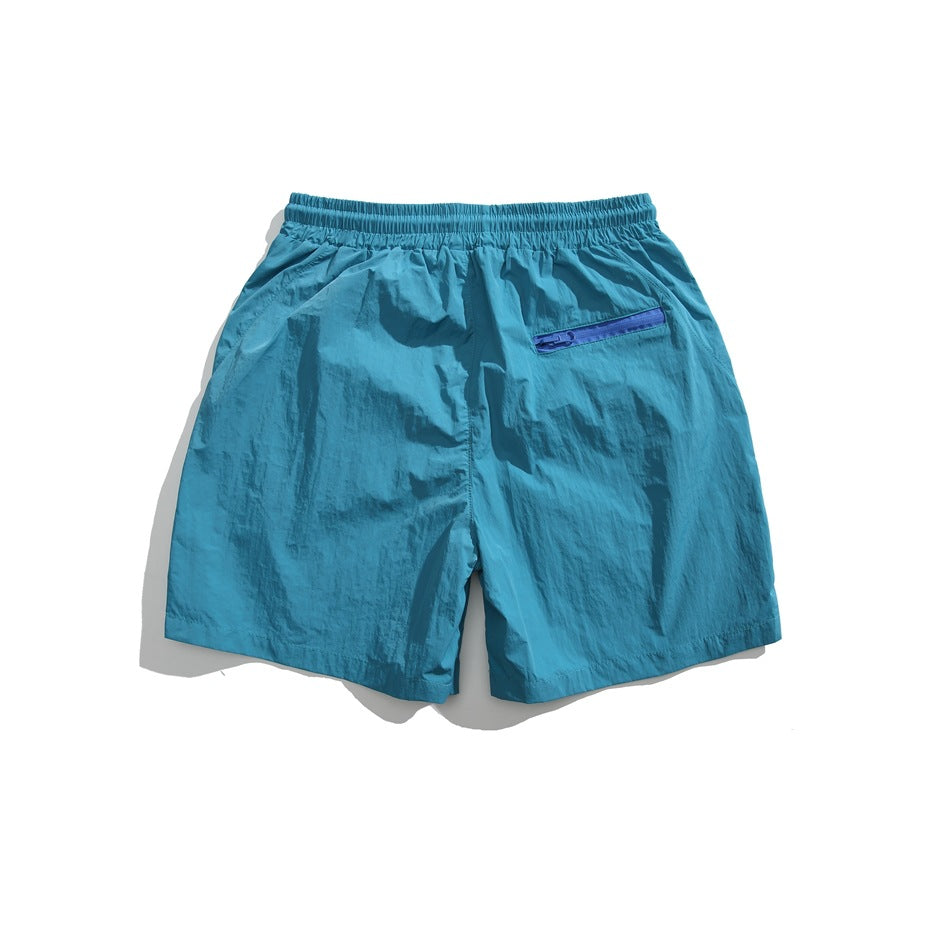 Back view of turquoise shorts with an elastic waistband and blue zip pocket.