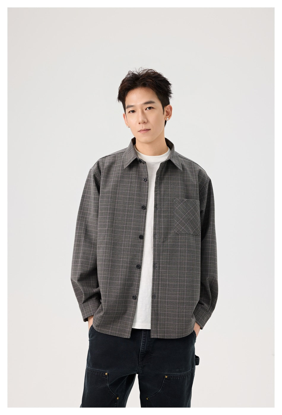 Model in a gray plaid button-front overshirt with a single chest pocket, layered over a white tee.