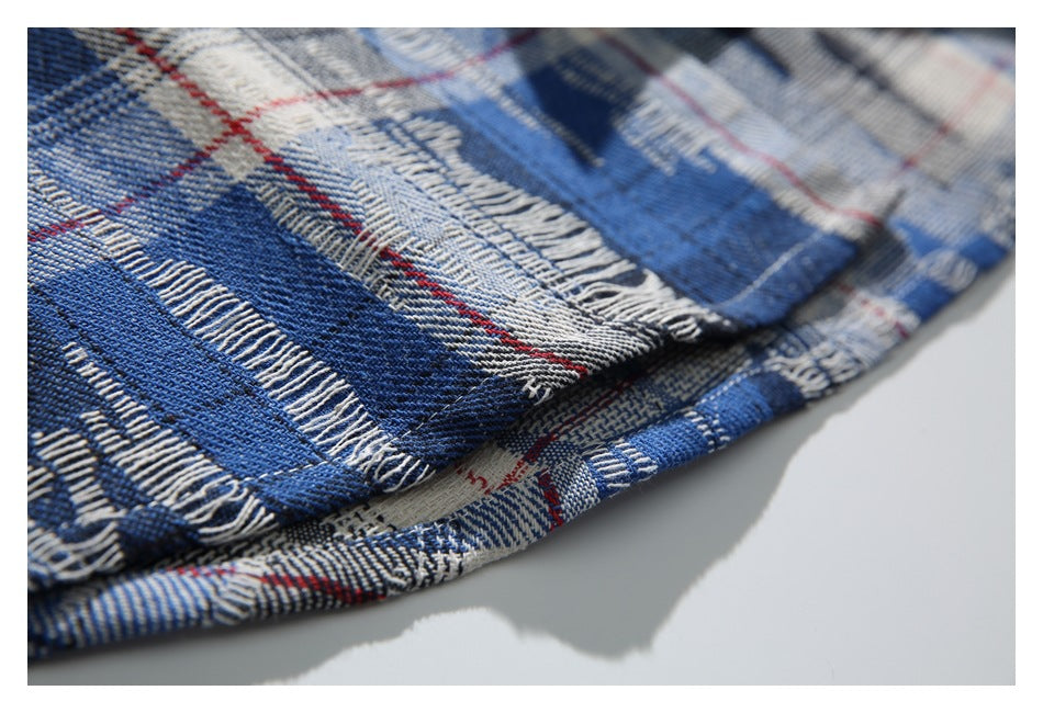 Close-up of the shirt's plaid fabric and stitched hem, showing blue, black, cream, and red lines.