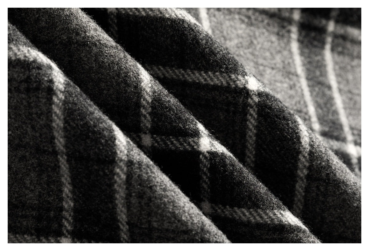 Extreme close-up of the fuzzy black, gray, and white plaid fabric texture.