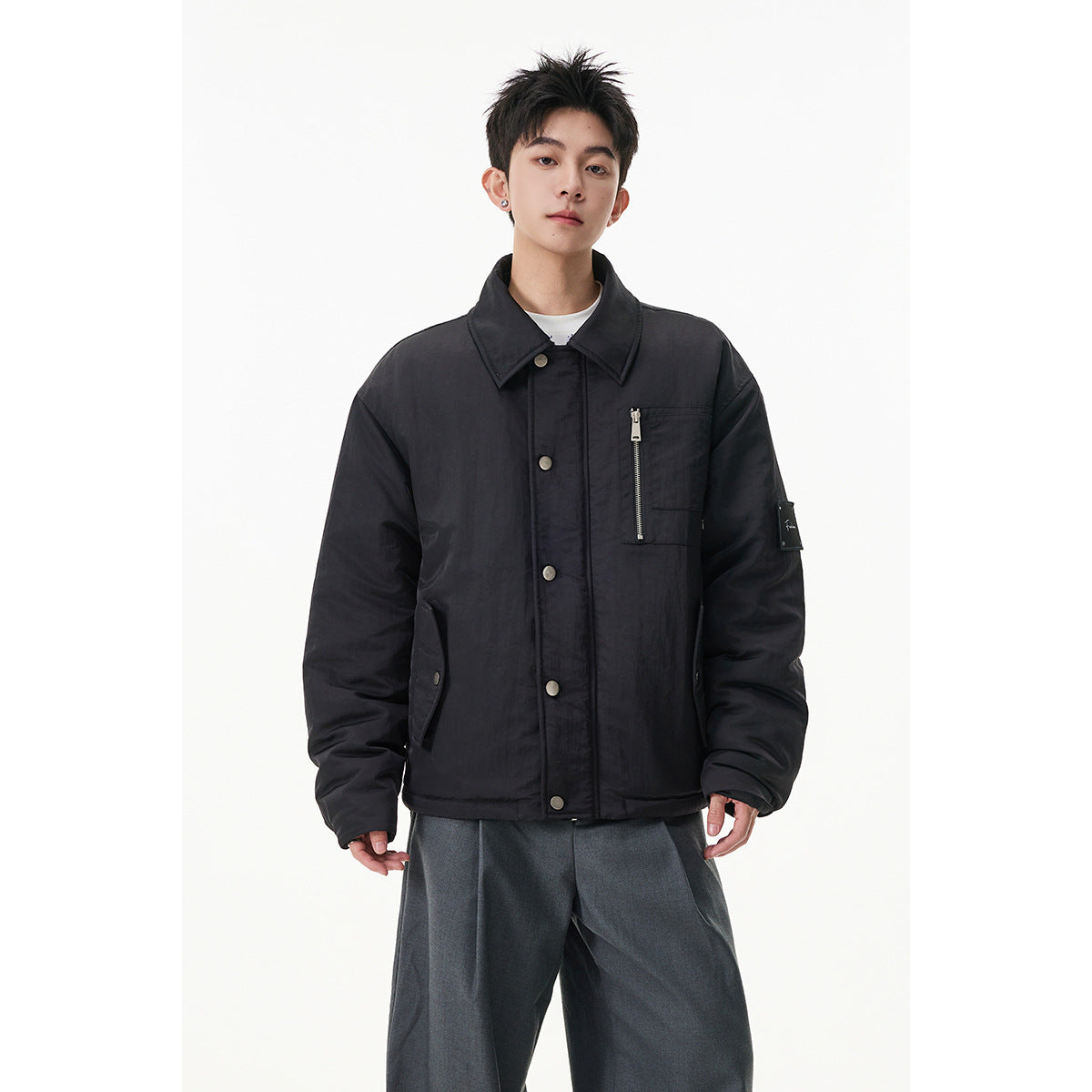 Model wearing a black button-front jacket with a pointed collar and vertical zippered chest pocket.