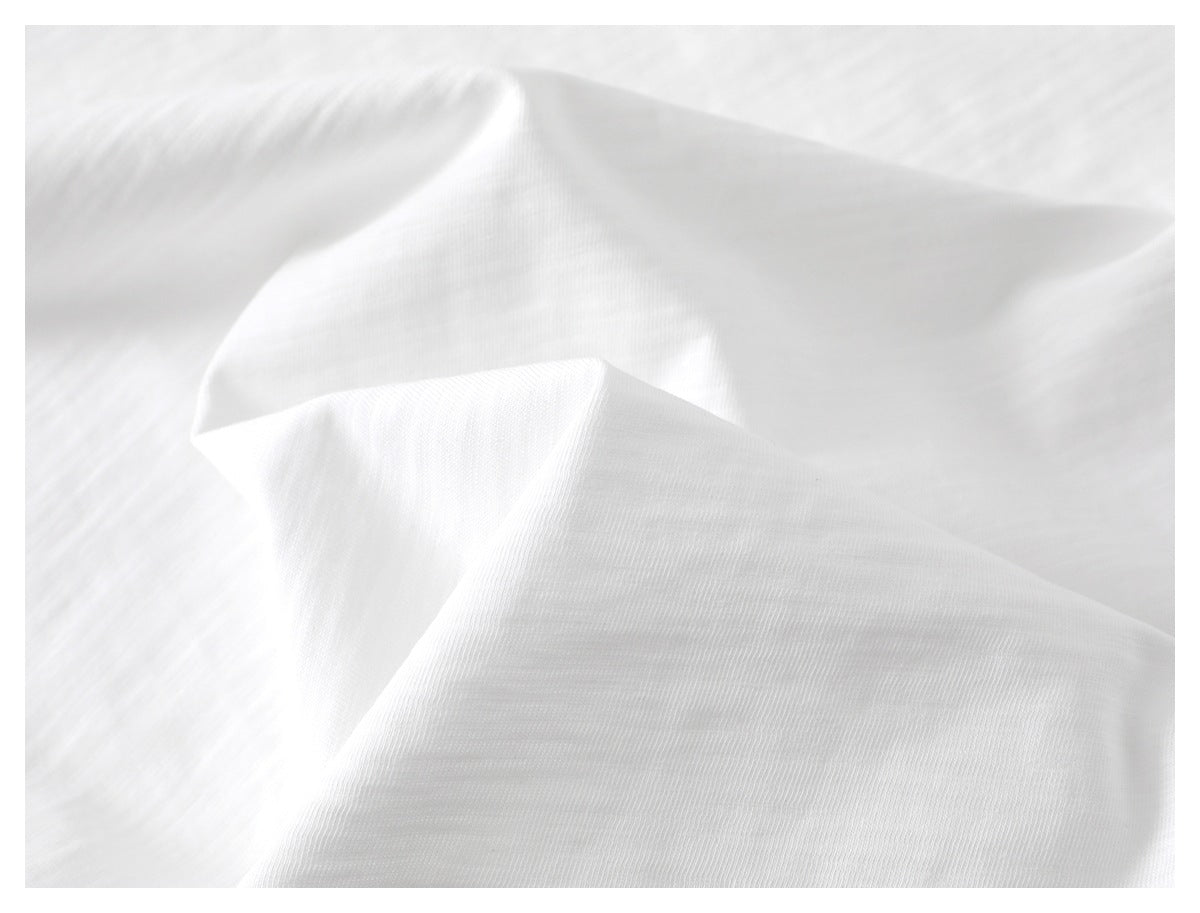 Close-up showing the soft folds and fine knit texture of white T-shirt fabric.
