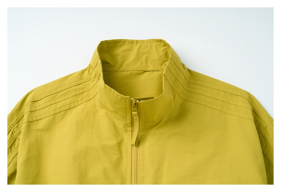Close-up front view of a mustard yellow jacket showing its stand collar, center zipper, and stitched shoulders.