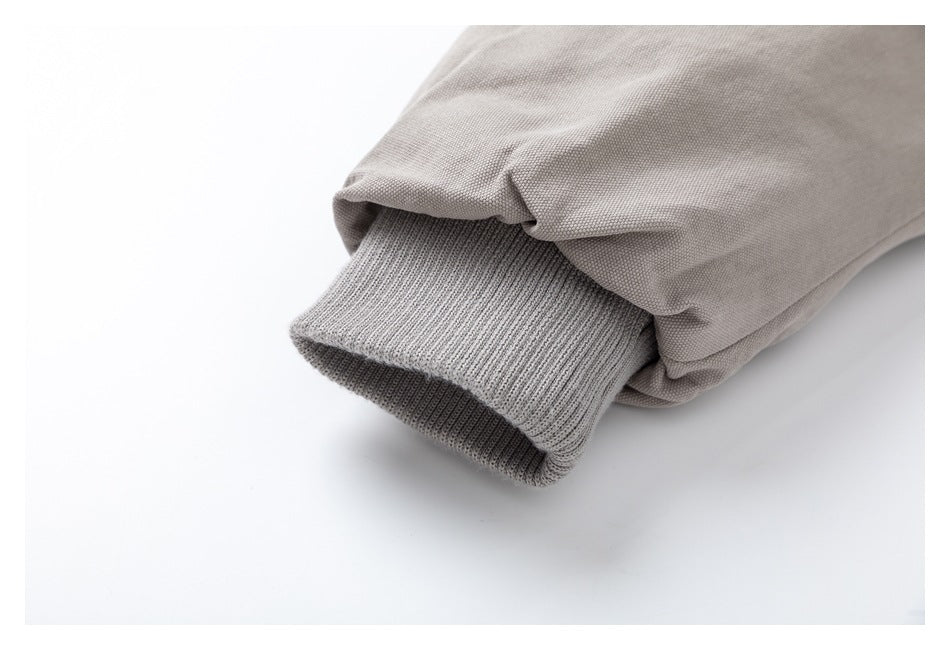 Close-up of a light taupe jacket sleeve ending in a gray rib-knit cuff.