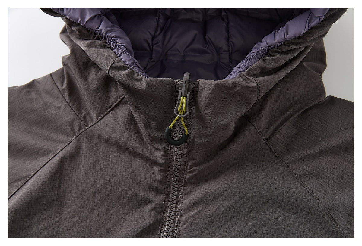 Close-up of the jacket’s dark padded hood lining, gathered edge and front zipper with a lime cord pull.