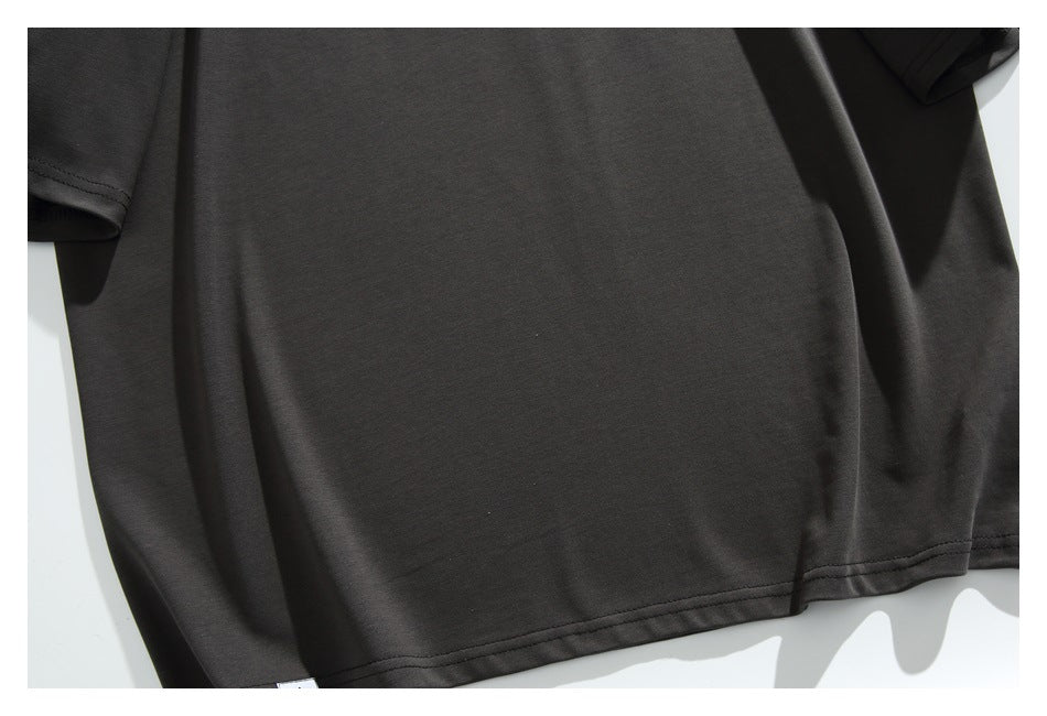 Close-up of the plain dark charcoal T-shirt body, sleeve edge, and lower hem.