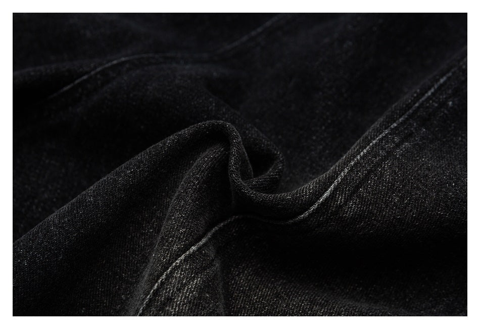 Close-up of black fabric folded to show its texture and stitched edge.