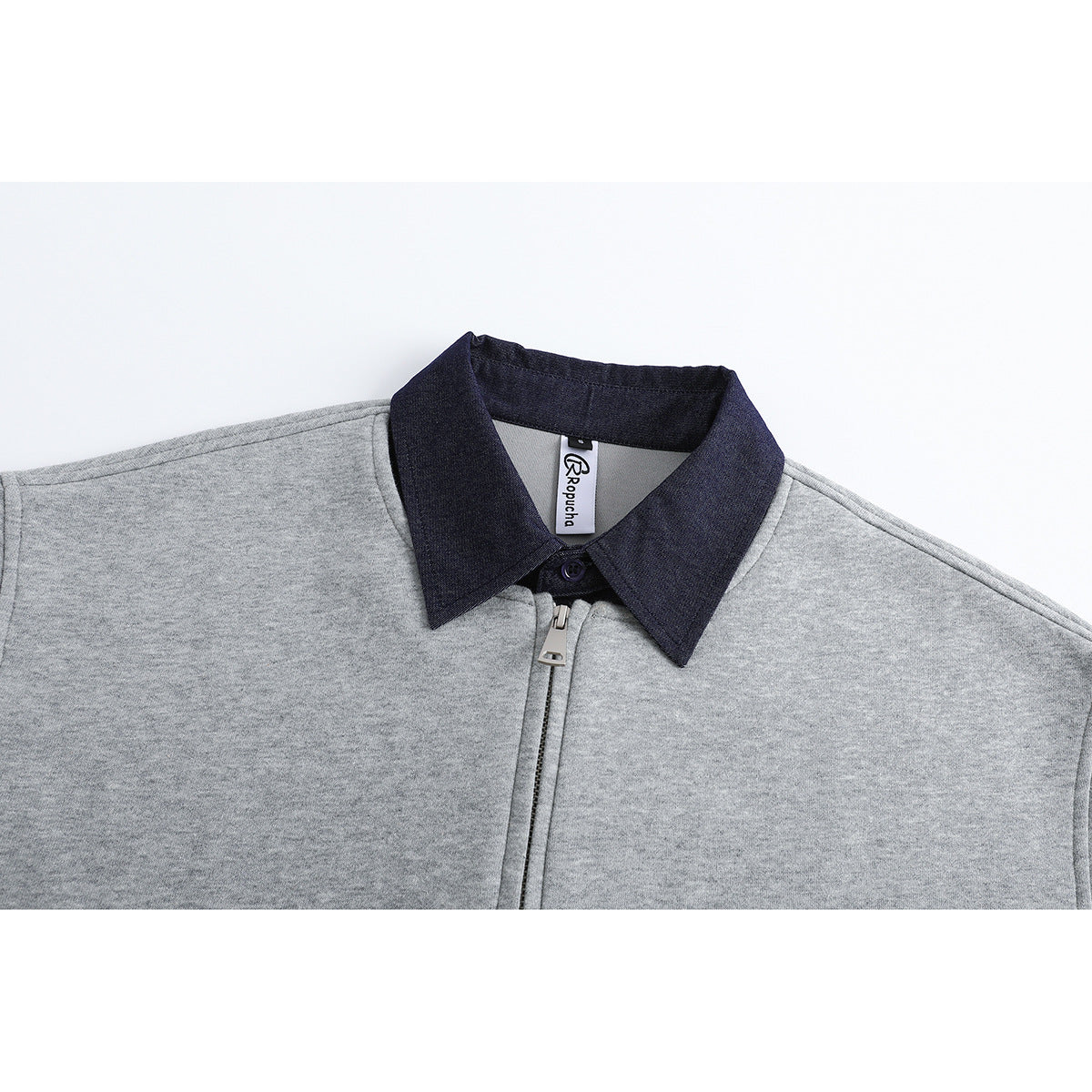 Close-up of a heather gray pullover's dark pointed collar, neck label, and short front zipper.