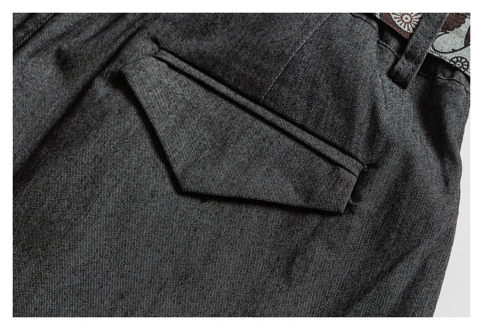 Close-up of dark charcoal trousers showing a flap pocket and a glimpse of patterned trim.