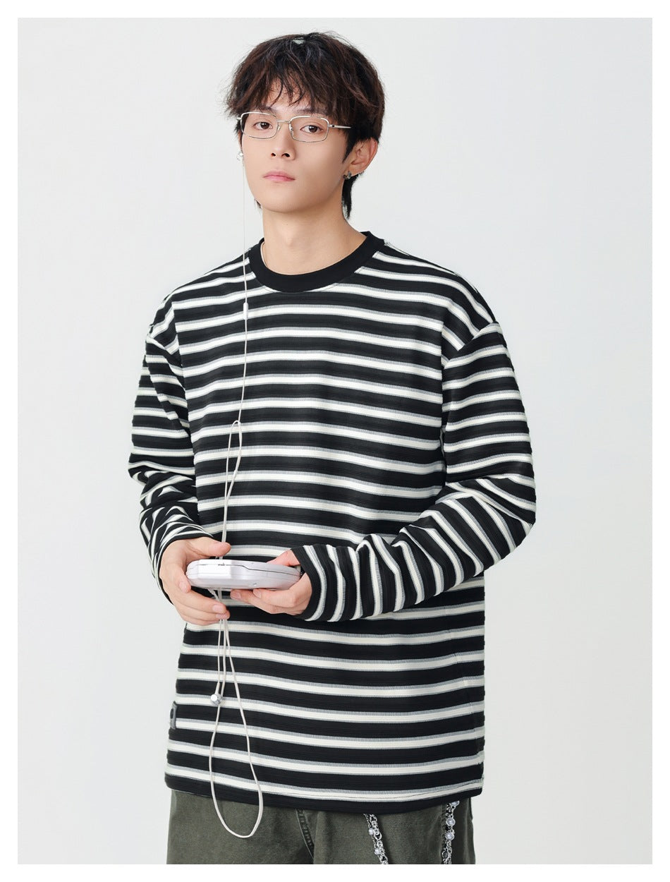 Model wearing a black, gray, and white striped long-sleeve shirt with a black crew neck; front view.