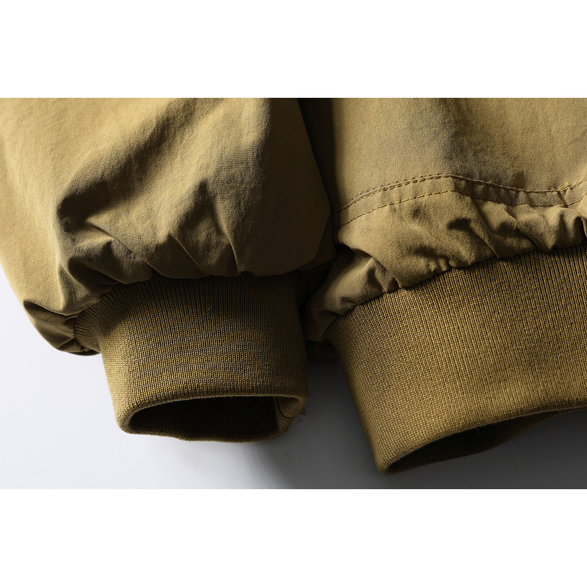 Close-up of the tan jacket's gathered sleeve and ribbed knit cuff.