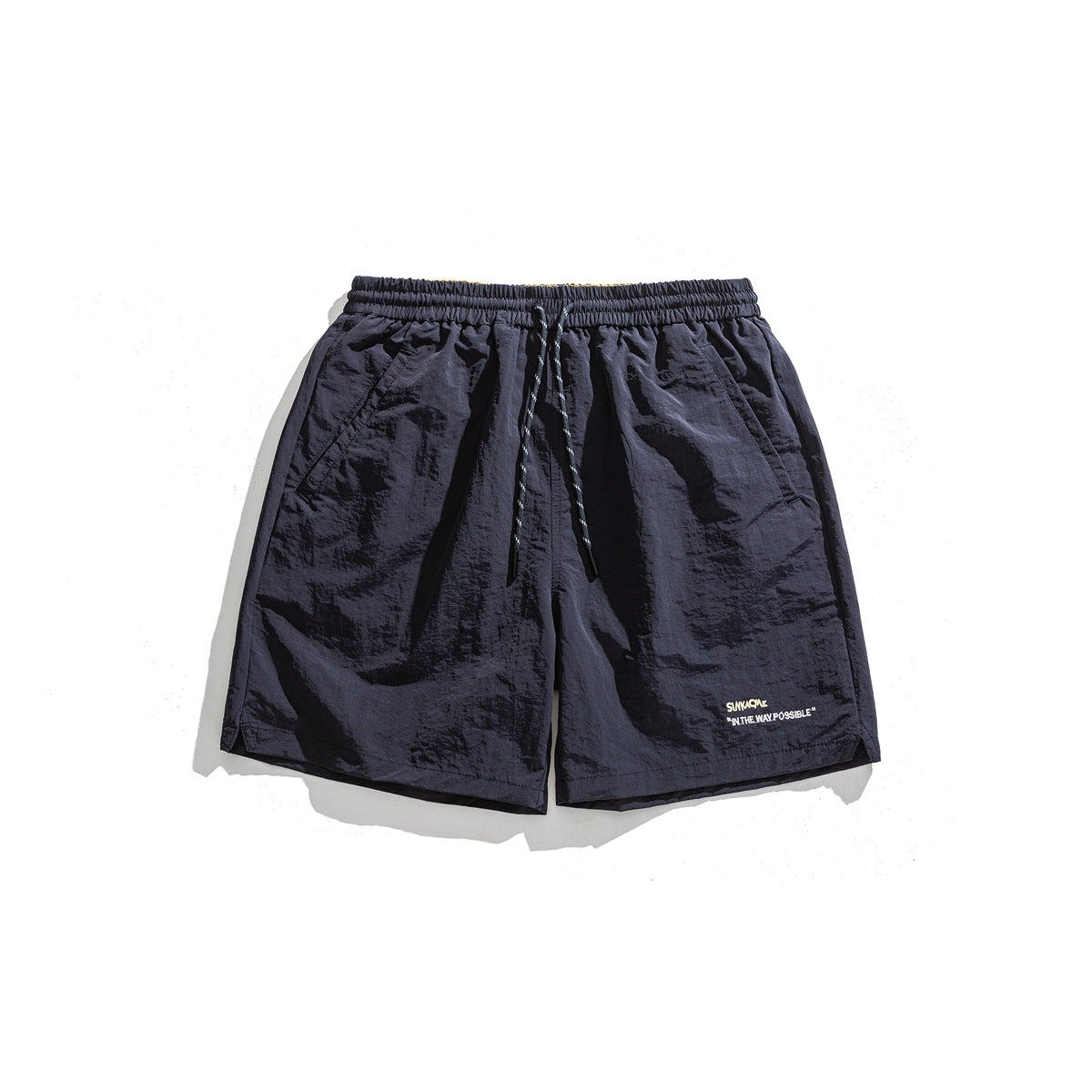 Navy drawstring shorts, flat lay front view, with side pockets and small embroidered text on the lower leg