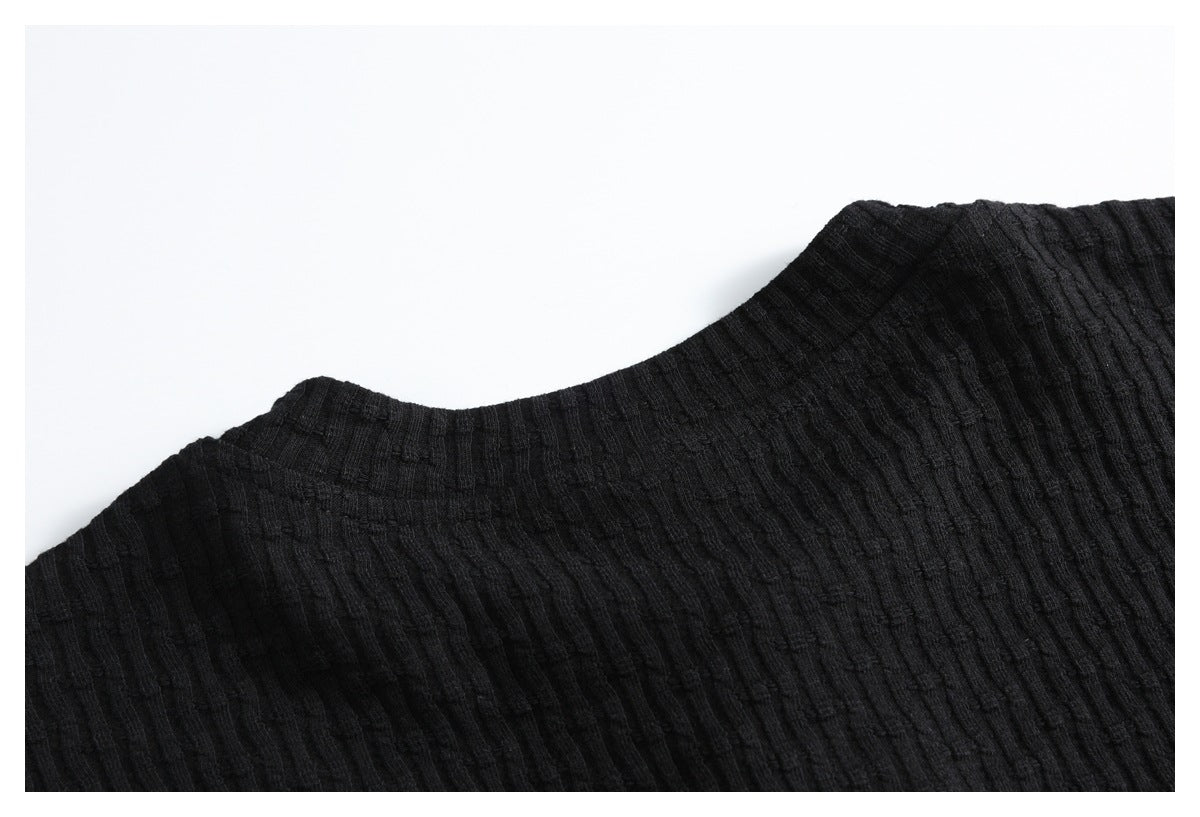 Close-up of the black ribbed garment's neckline and shoulder seam.
