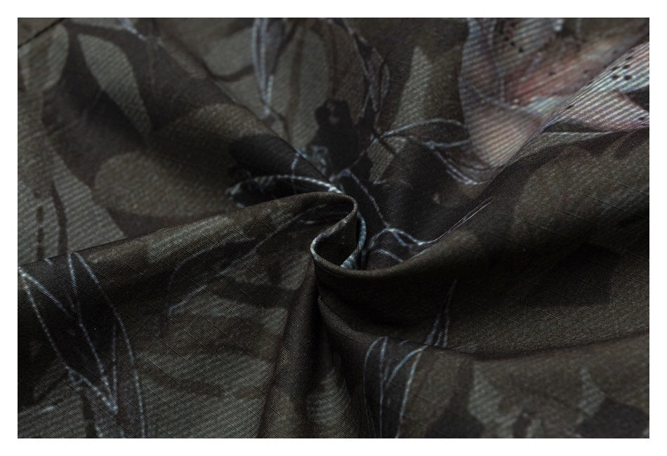 Close-up of dark patterned fabric folded to show its texture and muted blue-gray motifs.