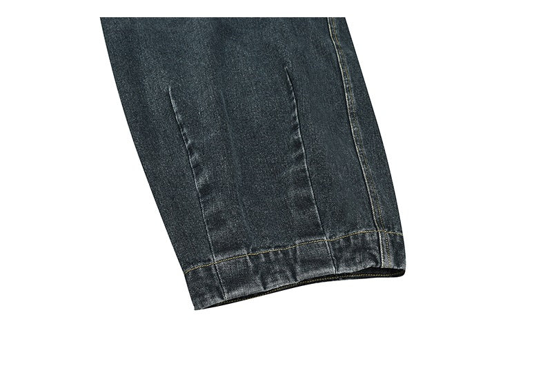 Close-up of a dark charcoal denim pant leg showing the hem and contrast stitching.