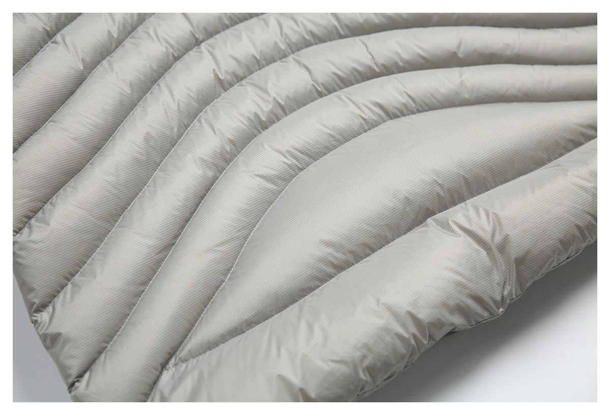 Close-up of a light gray quilted fabric item with narrow pinstripes and thick padded channels.