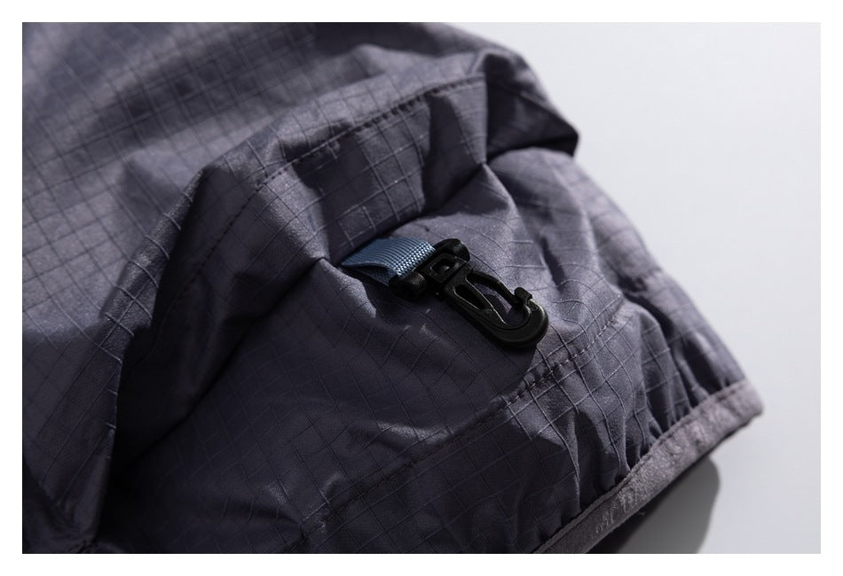 Close-up of a black hook and short webbing loop attached to the sleeve of a charcoal grid-pattern jacket.