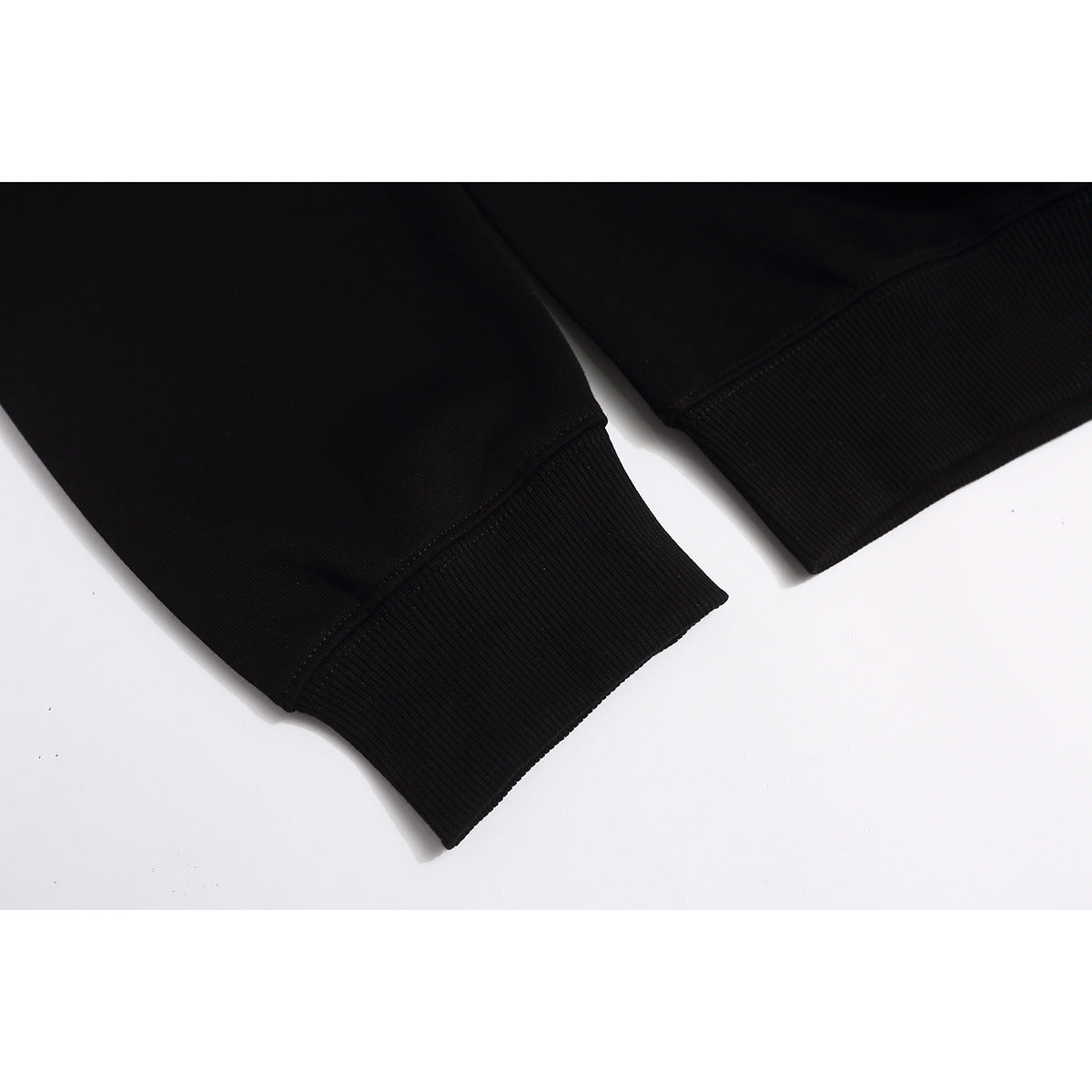 Close-up of the ribbed cuffs on the sleeves of a black sweatshirt.