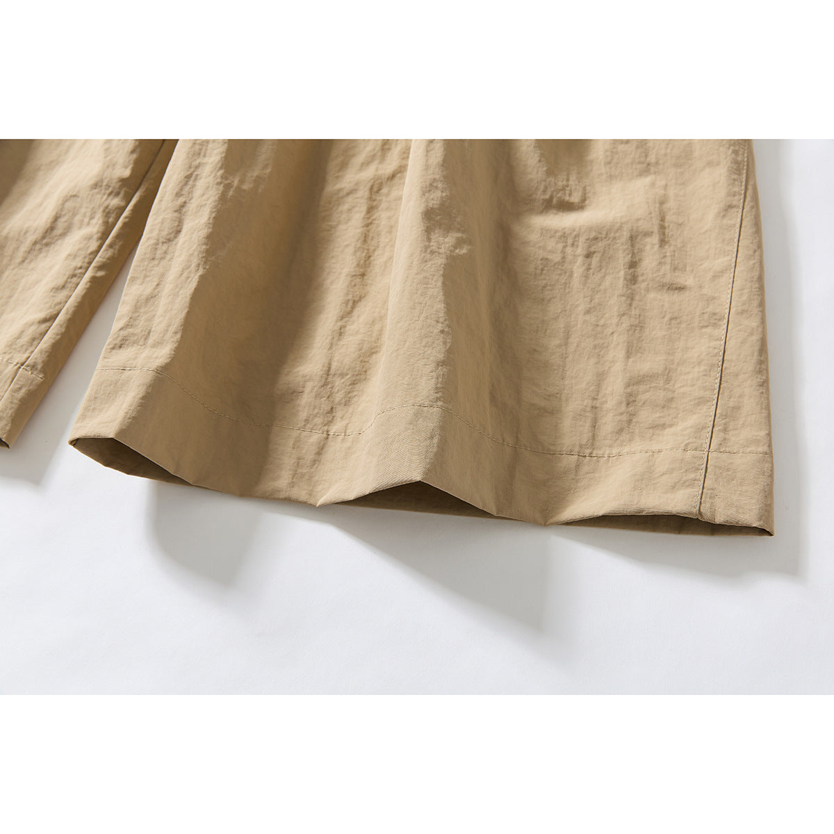 Close-up of the hem and leg opening on beige wide-leg shorts.
