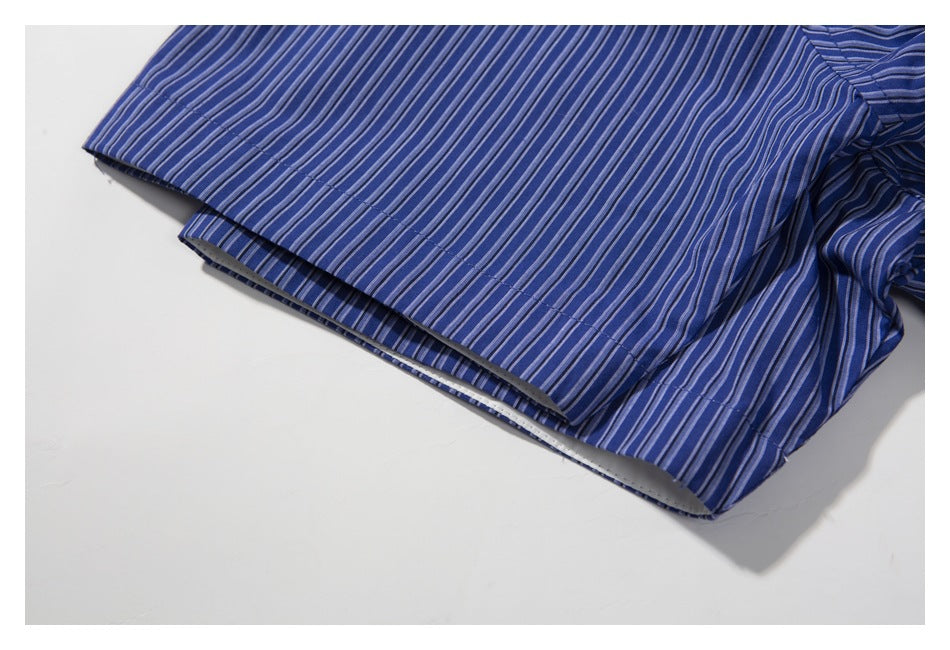 Close-up of a blue striped shirt sleeve and its folded, stitched edge.