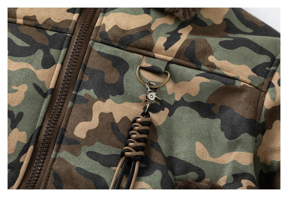 Close-up of a camouflage jacket chest pocket, zipper, and decorative cord attached to a metal ring.