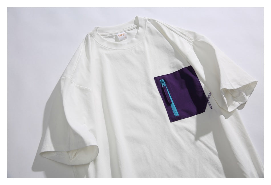 Close-up of a white T-shirt showing its purple chest pocket with a bright blue zipper.