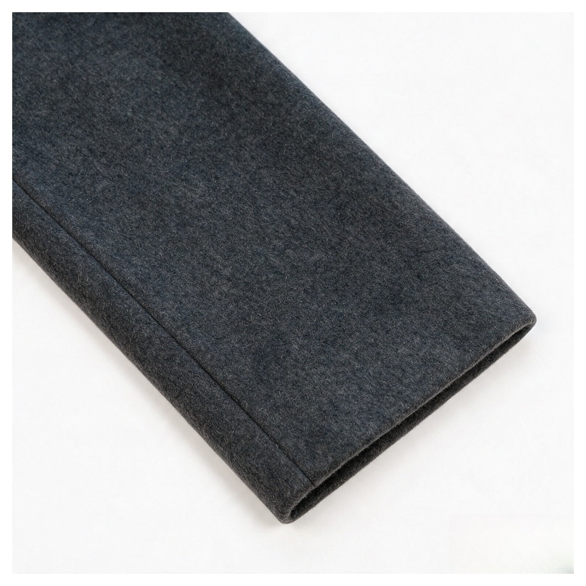 Close-up of a charcoal gray garment's folded edge and textured fabric against a white background.
