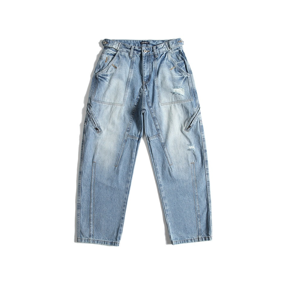 Front of light-blue washed denim jeans with patch pockets, side leg zippers, small rips and side waist tabs