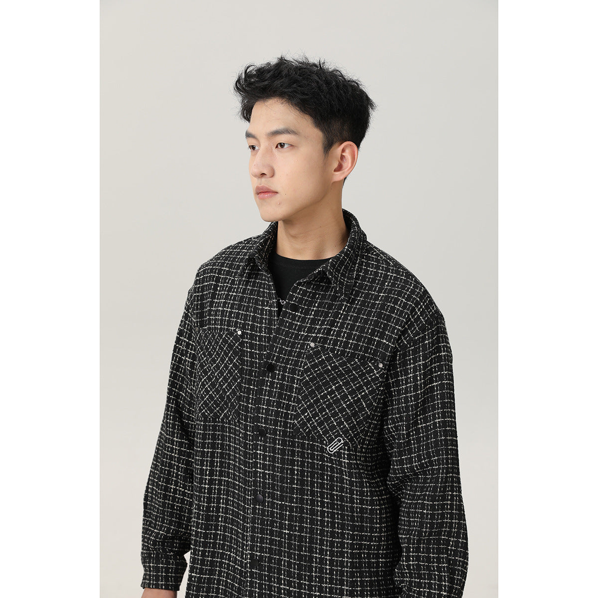 Model wearing a black-and-white grid overshirt with two chest pockets and a snap-button front, shown at an angle.