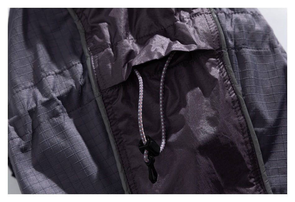 Close-up of a charcoal jacket's drawcord and black cord lock between contrasting panels.