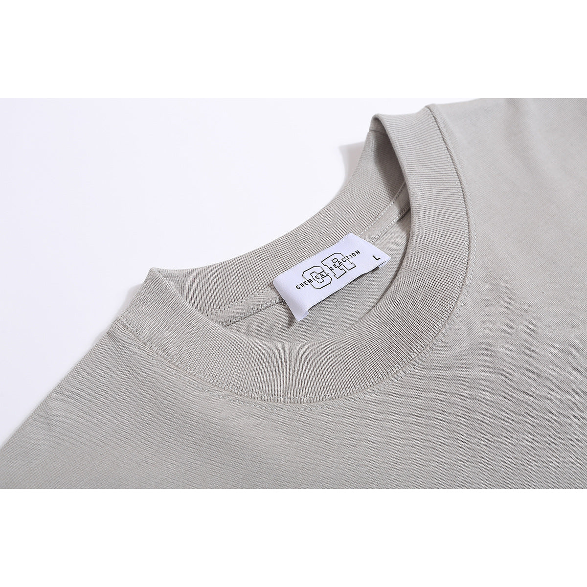 Close-up of a light gray T-shirt's ribbed crew neck and sewn-in white label.