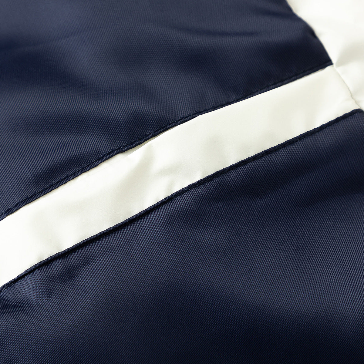 Close-up of navy jacket fabric with a broad diagonal ivory stripe.