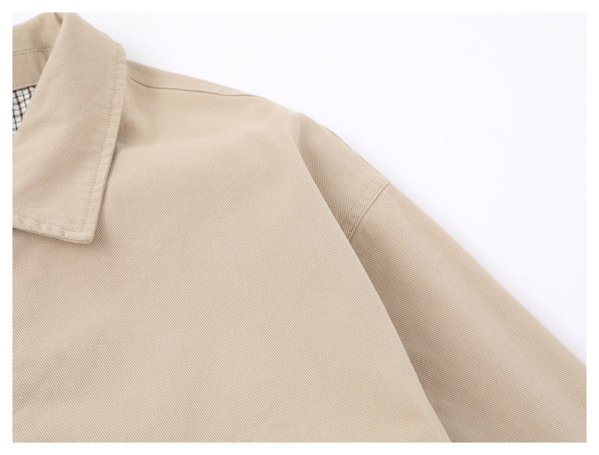 Close-up of the beige jacket's shoulder seam, sleeve, and twill-like surface.