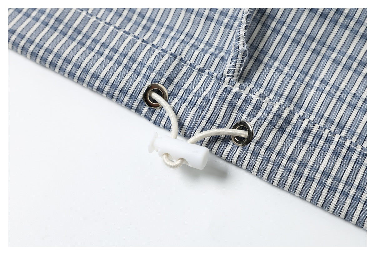 Close-up of a white drawcord toggle threaded through metal eyelets on a blue-and-white striped hem.