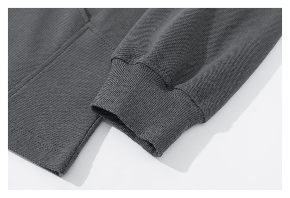 Close-up of a charcoal sweatshirt sleeve with a wide ribbed cuff and stitched hem.