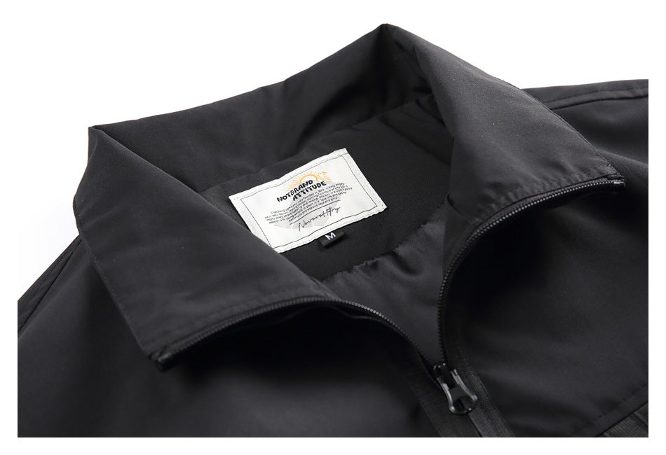 Close-up of a black garment's collar, front zipper, and sewn neck label.