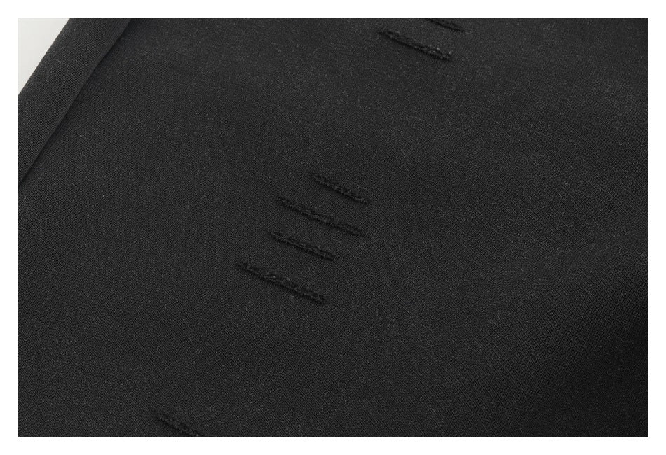 Close-up of black fabric with several short distressed slits.