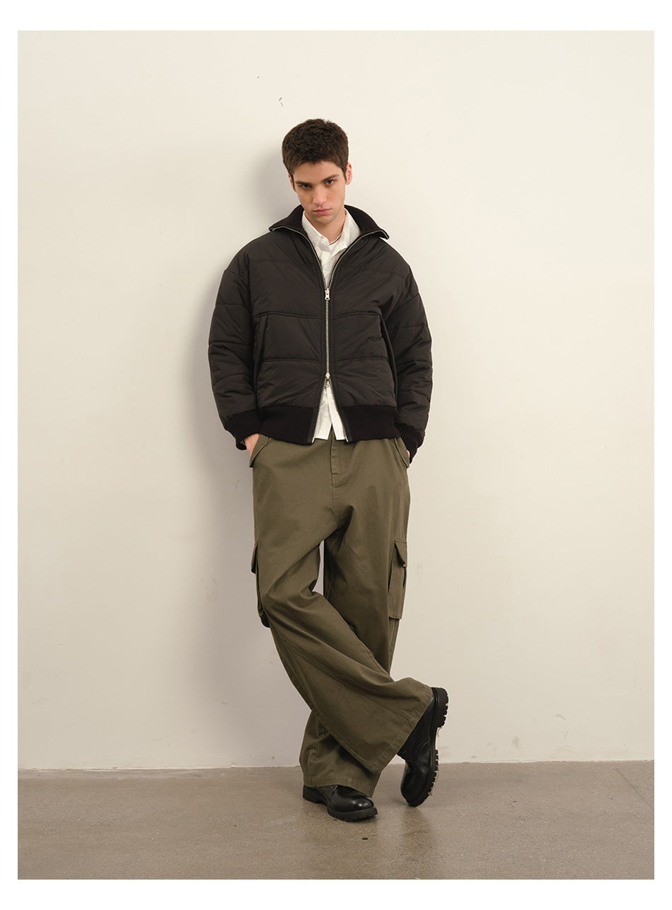 Model wearing a black quilted zip jacket with ribbed trim and loose olive cargo trousers.