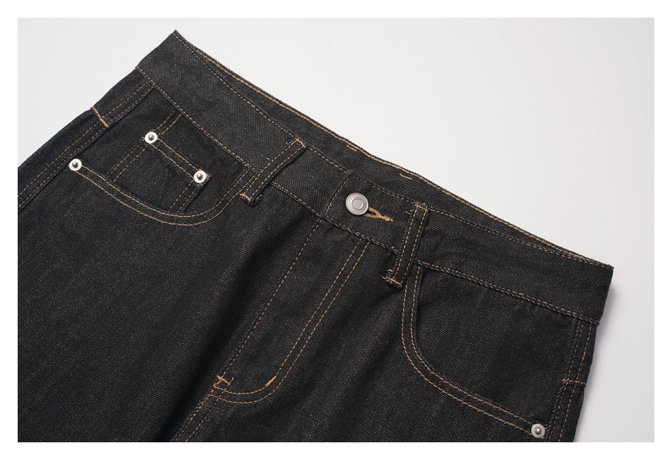 Close-up of the dark denim jeans' front waistband, button, belt loops, pockets, and contrast stitching.