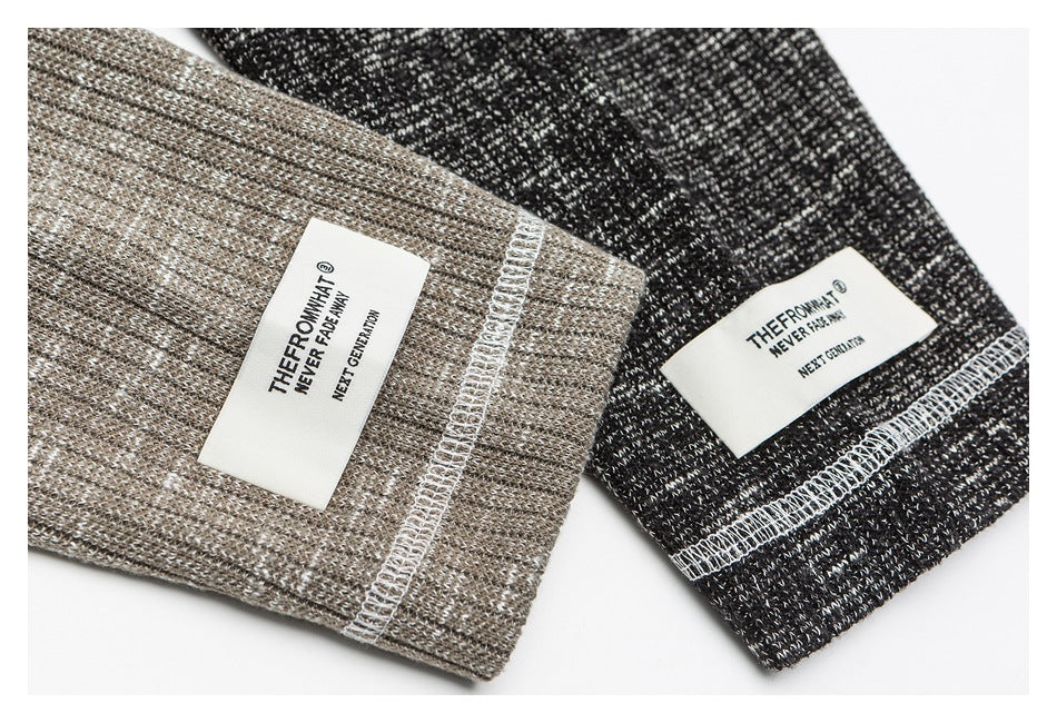 Close-up of taupe and charcoal marled shirt cuffs with white stitched labels and contrasting overlock seams.