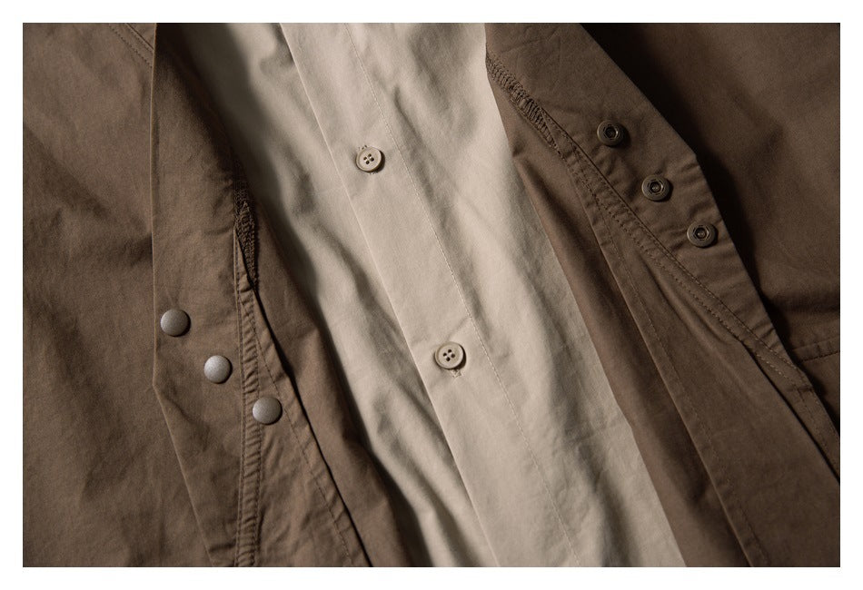Close-up of dark brown snap buttons beside a light beige button-front panel.