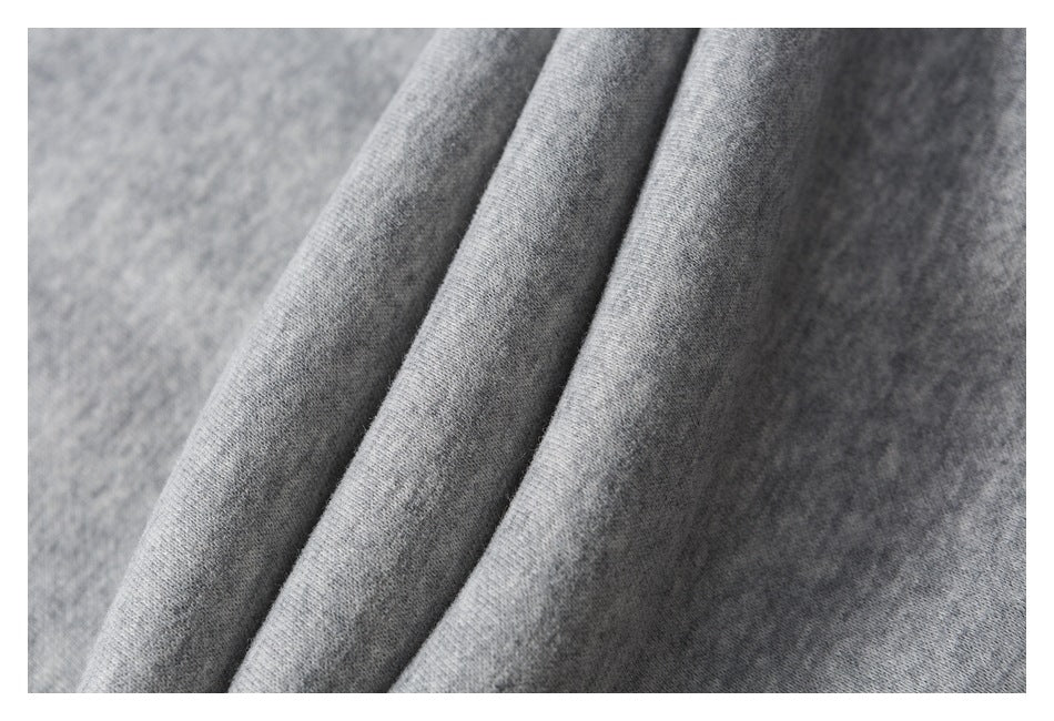 Macro view of the soft-looking heathered gray fabric and folded seams of the pants.