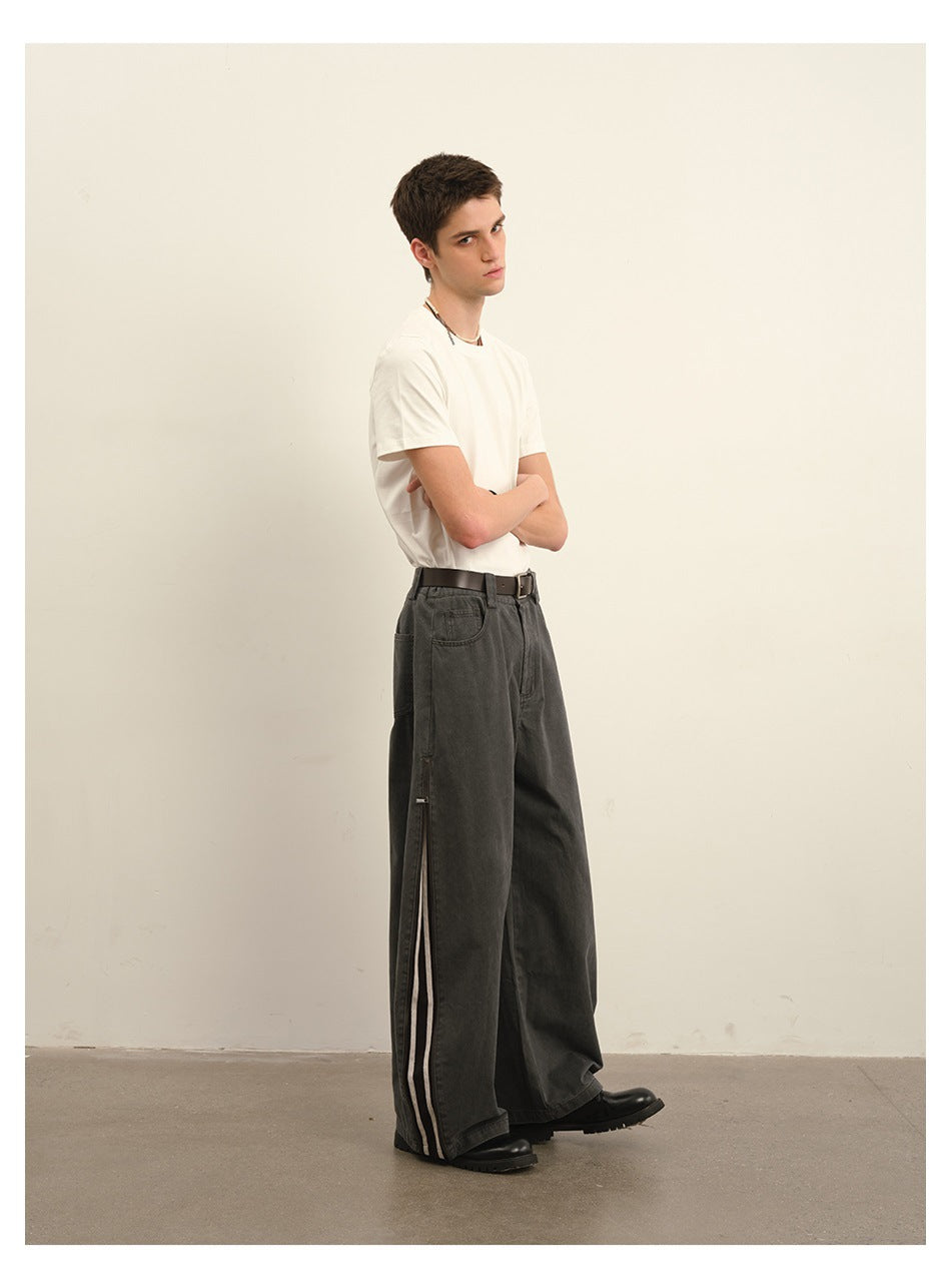 Model wearing washed gray wide-leg pants with a white tee and belt, showing side zip slit with stripe detail