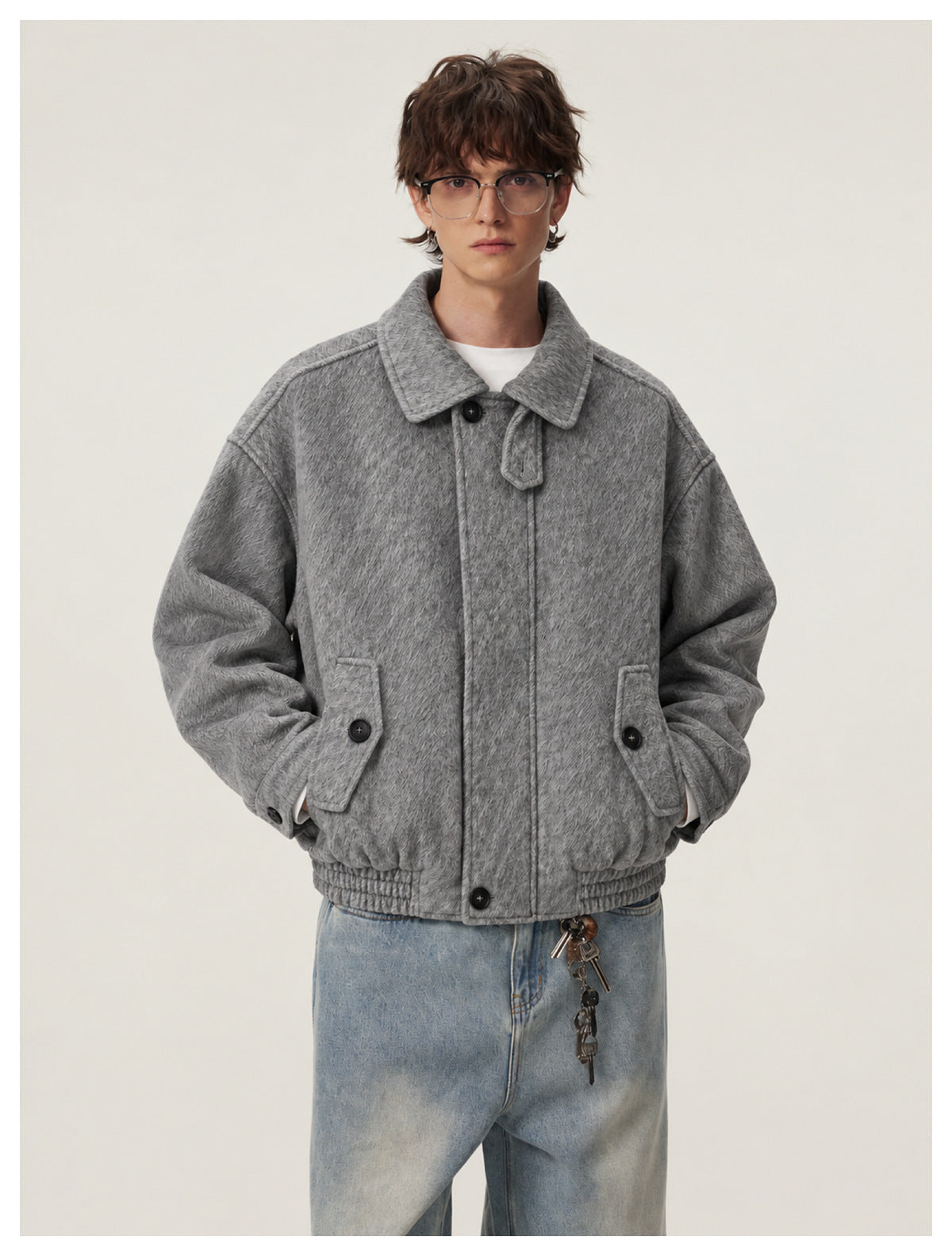 Model wearing a gray textured button-front jacket with a wide collar and flap pockets over a white shirt.