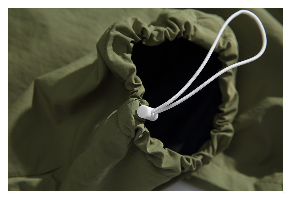 Close-up of a gathered olive-green pant opening with a white drawcord and cord lock.